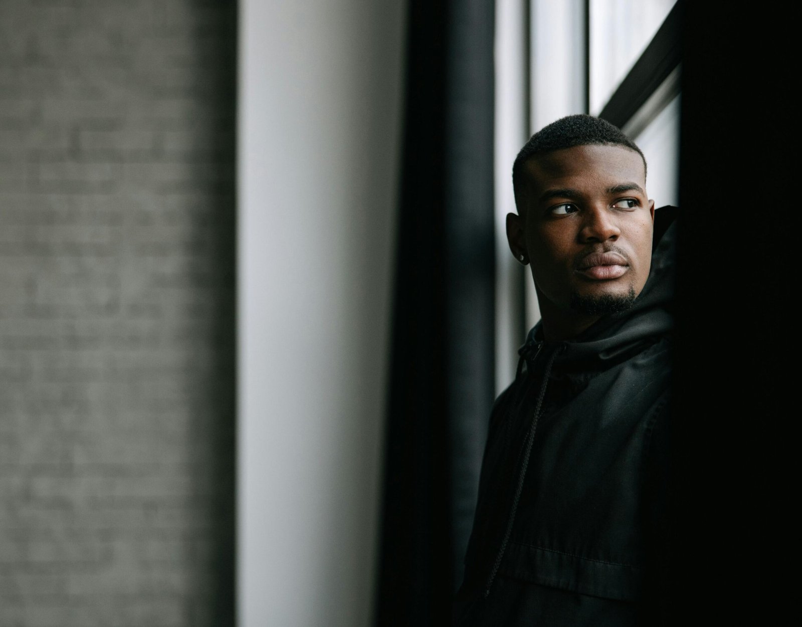 Portrait of a thoughtful young man gazing outside, captured indoors with natural light.